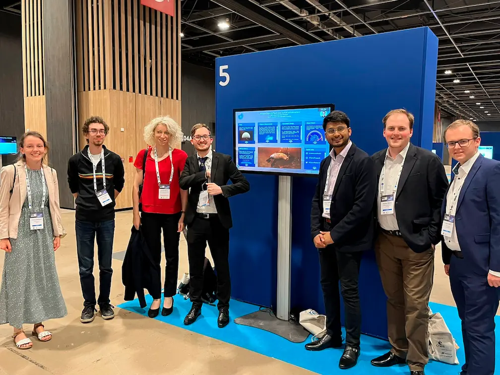 Conex members stood around a screen displaying the Astraeus interactive presentation